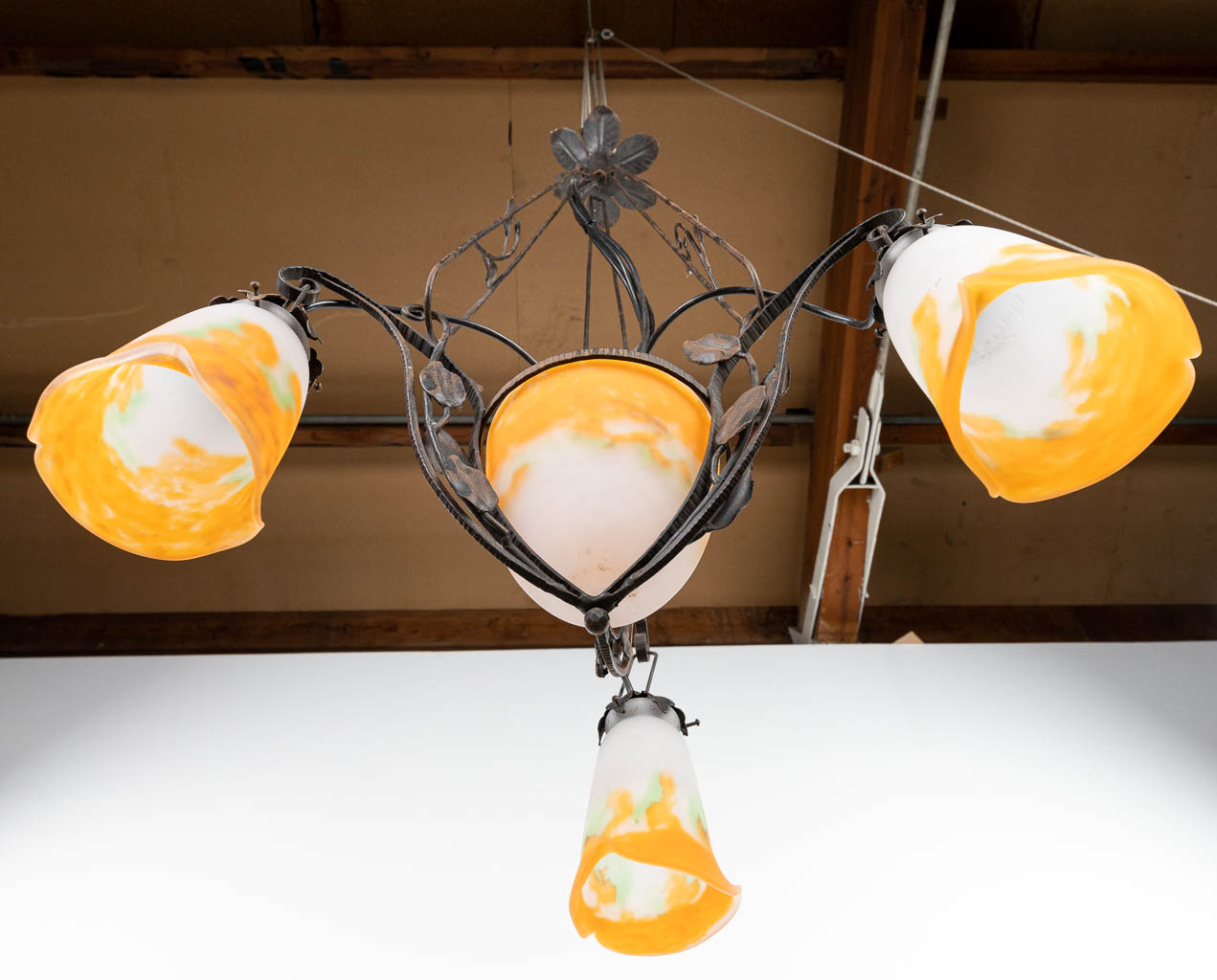 A chandelier in art deco style made of cast-iron and finished with pate-de-verre shades marked Muller. (H:100cm)