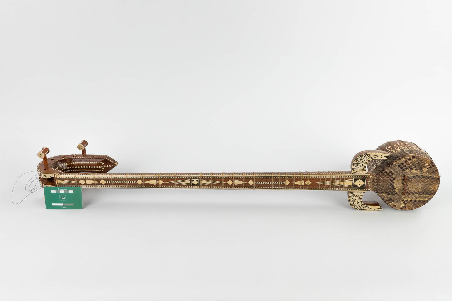 Een Oosters muziekinstrument met 6 snaren, slangenleder en ingelegd met been. 20ste eeuw. (D:13 x W:15 x H:93 cm)