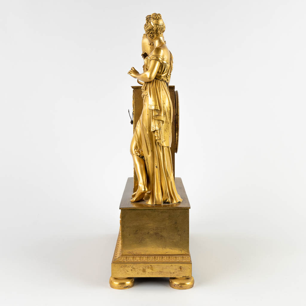 Een schouwklok met figuur van een galante dame, vuurverguld brons, Empire, 19de eeuw. (D:13 x W:32,5 x H:44 cm)