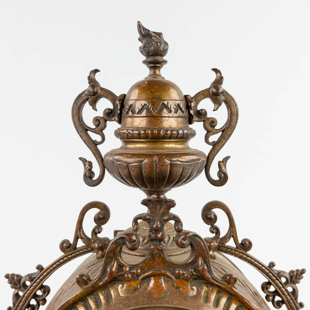 Een driedelige schouwgarnituur, klok met kandelaars, gepatineerd brons. Circa 1900. (D:11 x W:22 x H:43 cm)