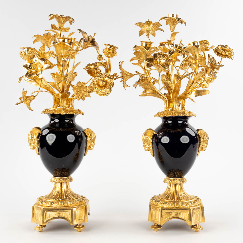 A pair of candelabra, gilt bronze on porcelain and decorated with flower decor. (D:30 x W:28 x H:53 cm)
