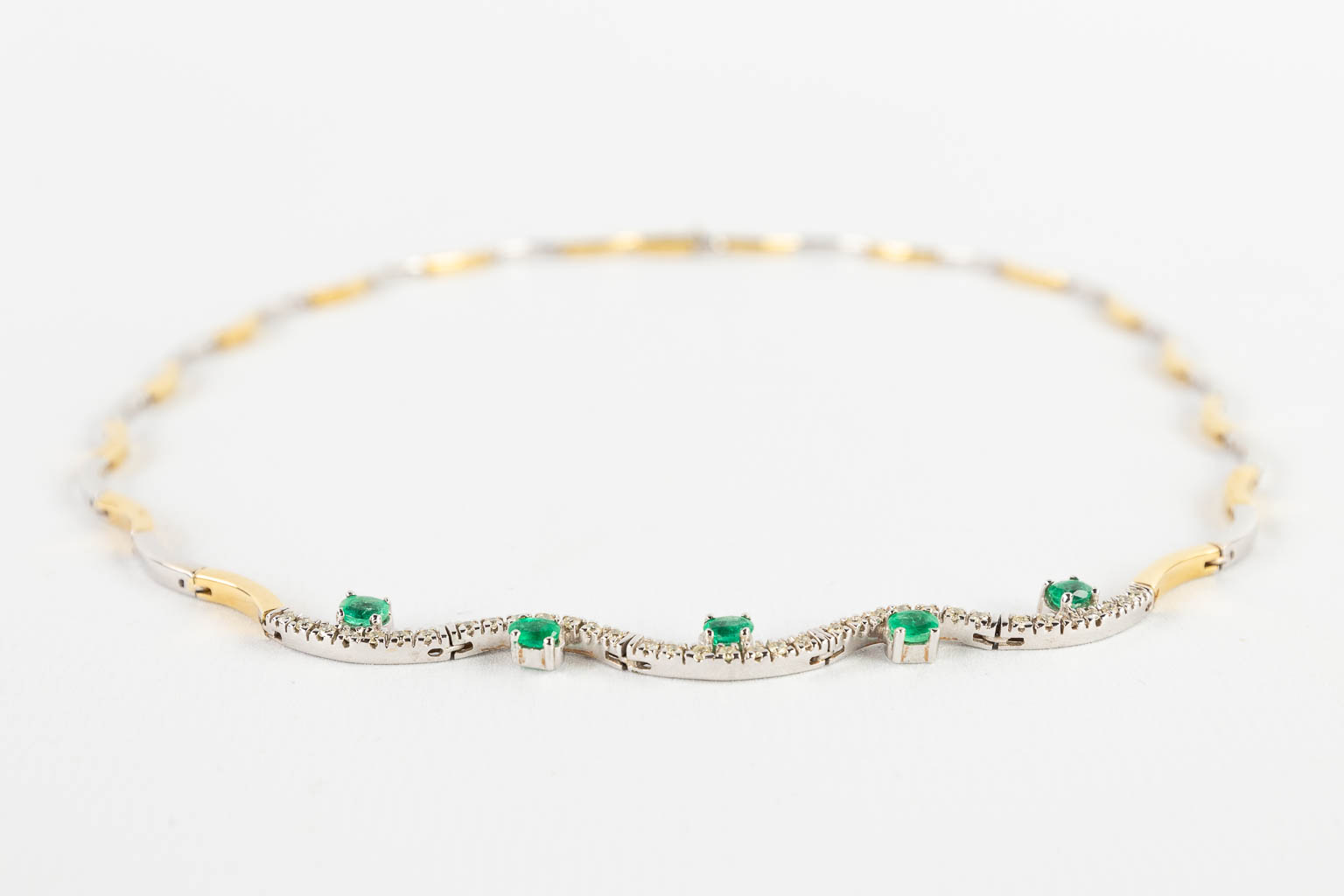 A necklace, 18 karats yellow and white gold, decorated with green, probably, emeralds. 24,67g.