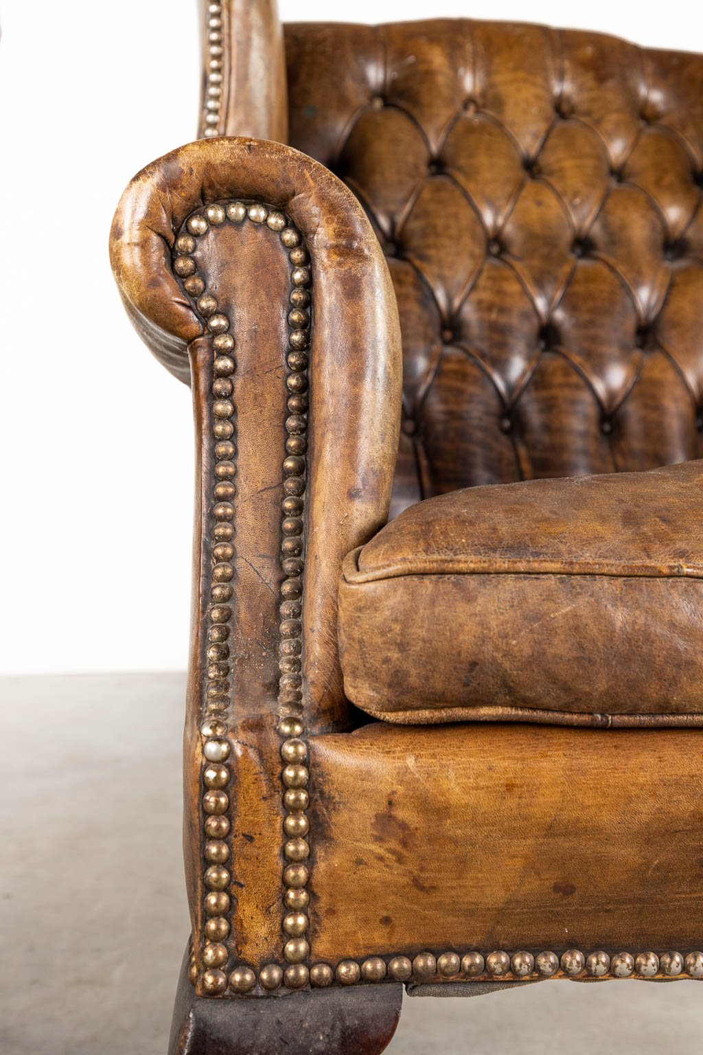 A pair of armchairs, Chesterfield style, leather and wood. (D:85 x W:78 x H:107 cm)