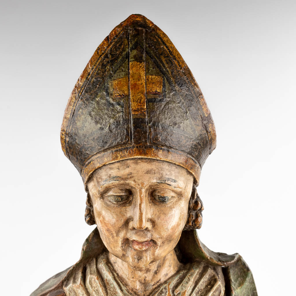 Een antieke houtsculptuur van een Heilige met staf en mijter, originele polychromie. 18de eeuw. (D:28 x W:38 x H:74 cm)