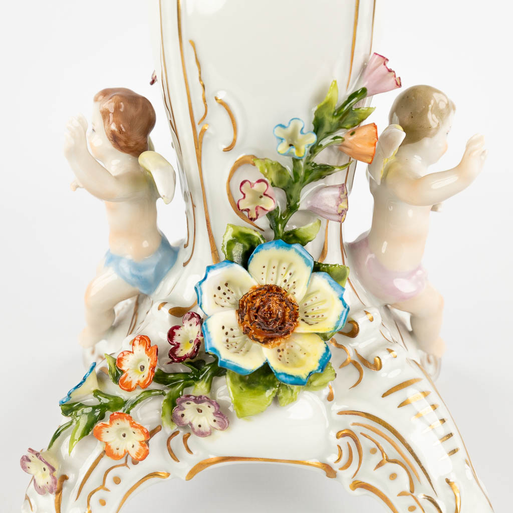 A table candle holder, porcelain decorated with flowers and putti. 20th C. (D:38 x W:38 x H:47 cm)