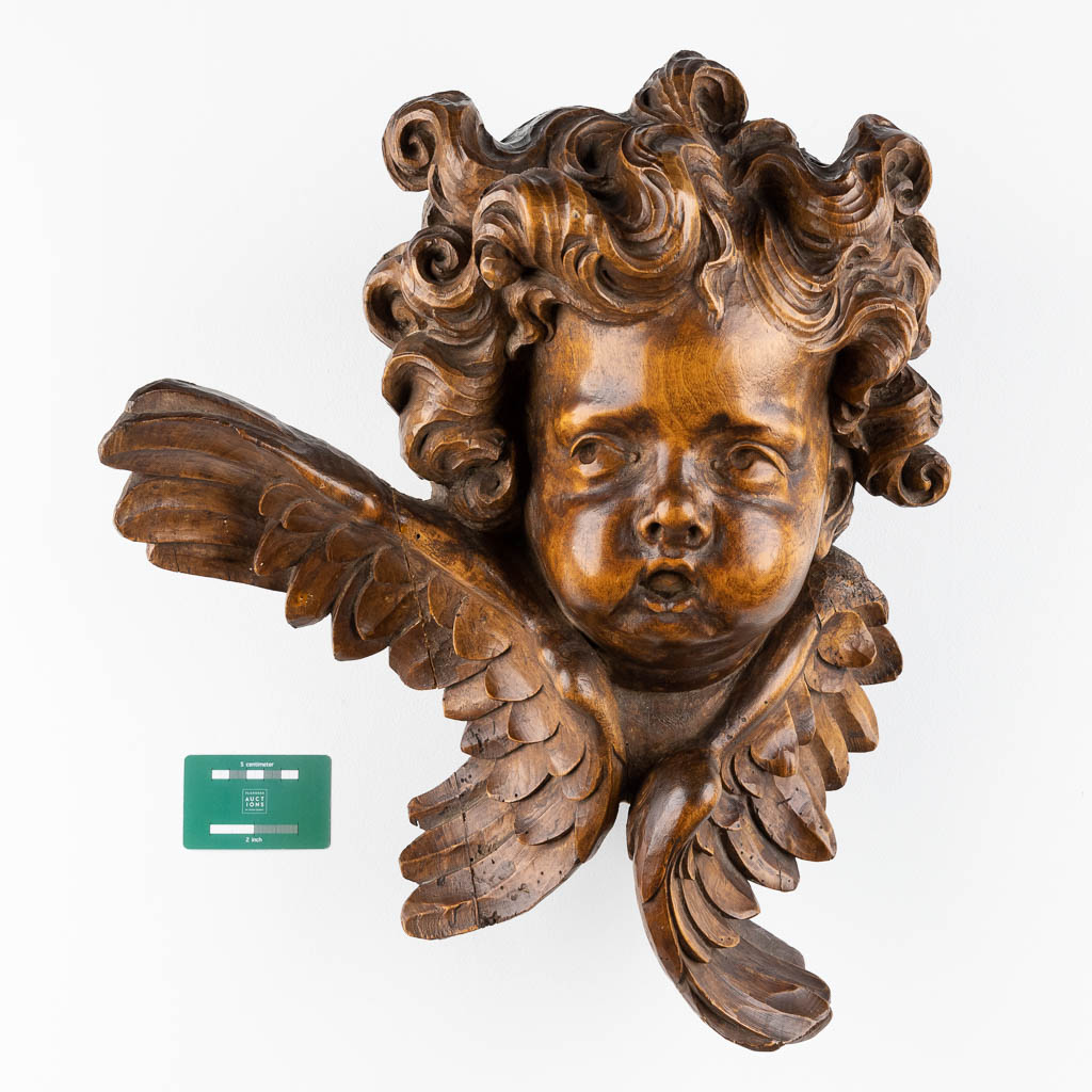 A wood-sculptured large head of an angel, Baroque style, 19th C. (D:27 x W:42 x H:48 cm)