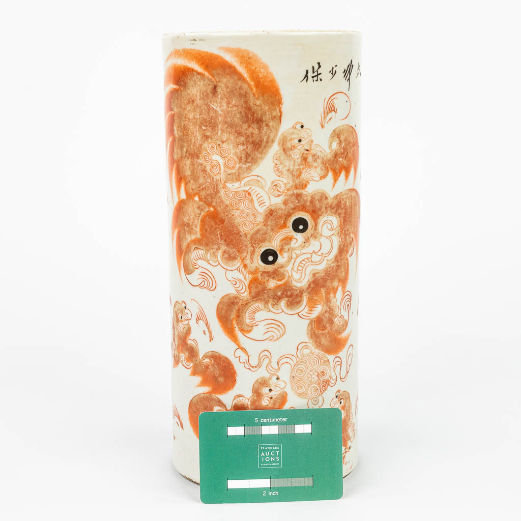 A Chinese hat stand made of porcelain and decorated with a red foo dog. (H:27,5cm)