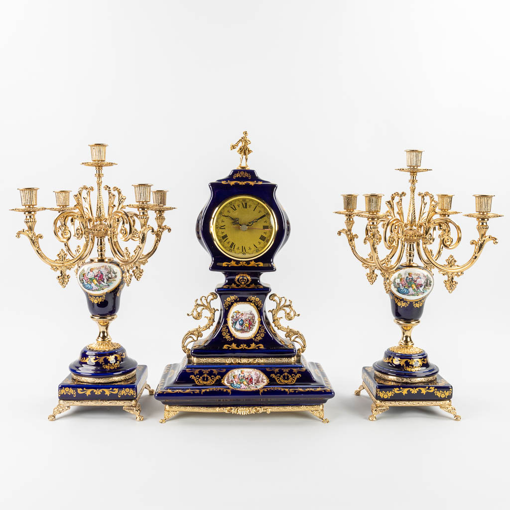 A three-piece porcelain mantle garniture clock and candelabra. (L: 19 x W: 30 x H: 50 cm)