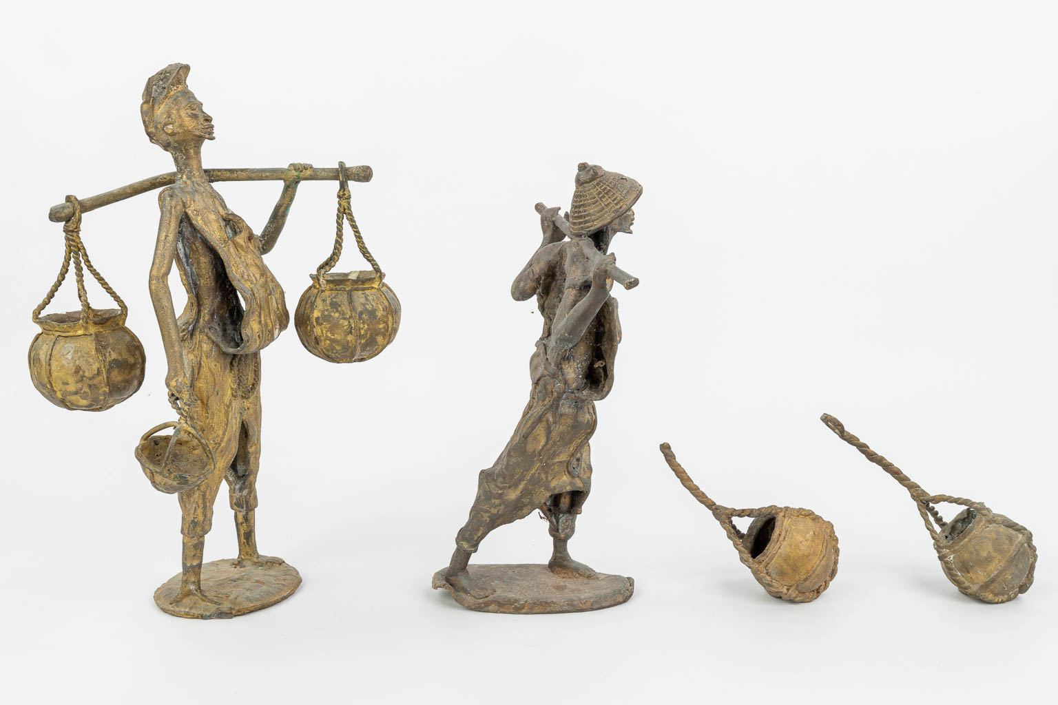 Een collectie van twee bronzen beelden van Oosterse figuren met manden. (H:36cm)