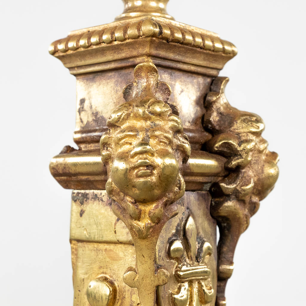 Een paar haardvuurbokken, verguld brons en afgewerkt met leeuwenkoppen en poten. 19de eeuw. (D:16 x W:23 x H:61 cm)