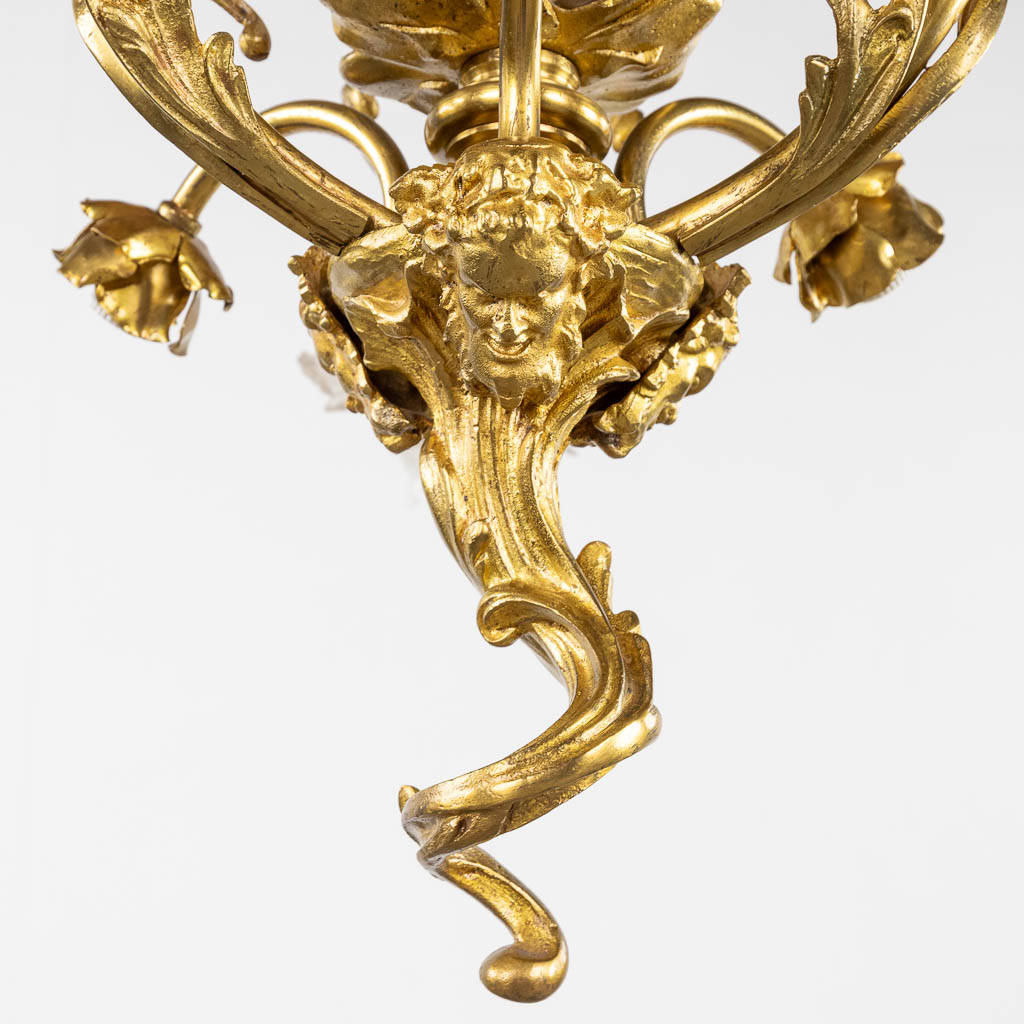 Een luchter met glazen flambeau, verguld brons afgewerkt met saterfiguren. (H:88 x D:54 cm)