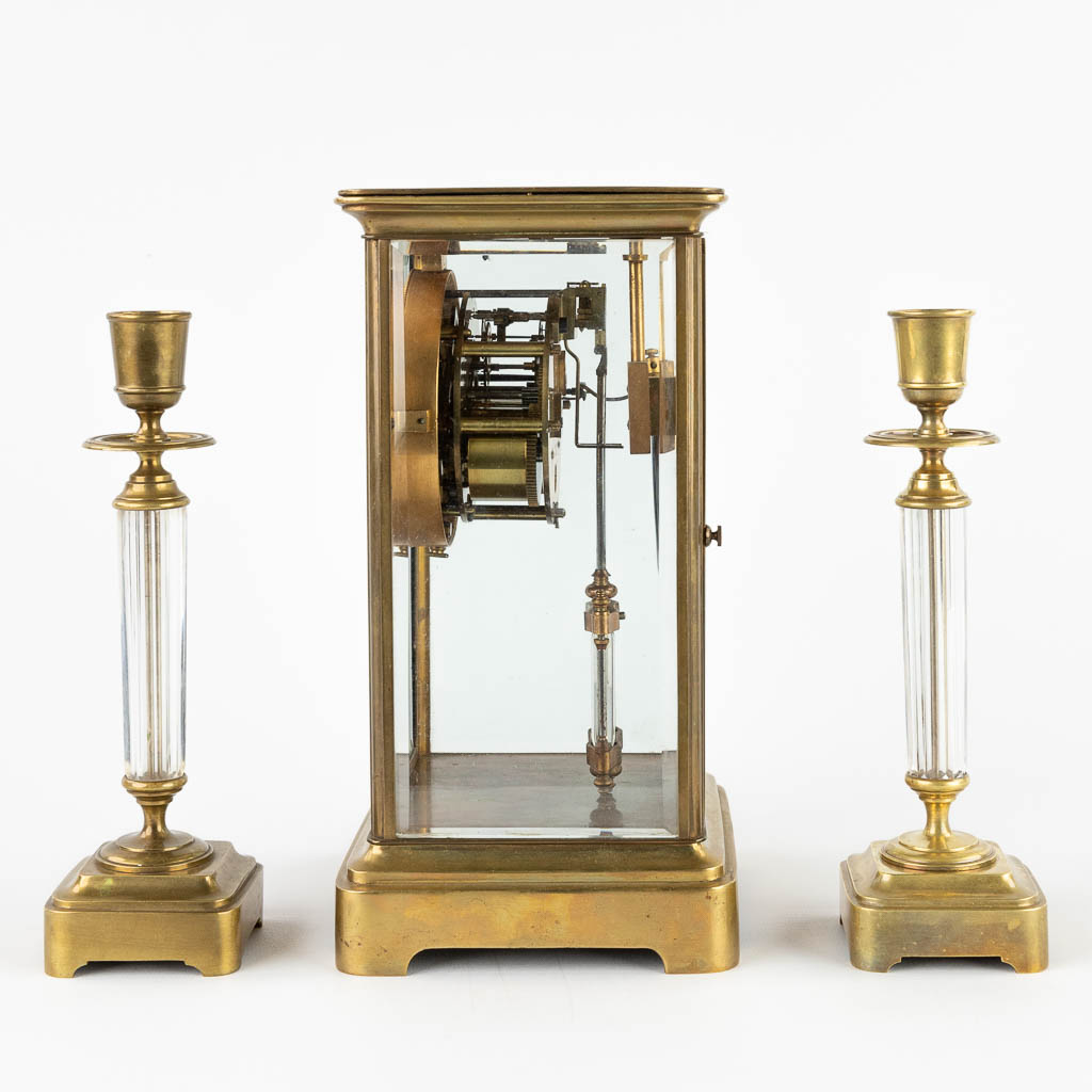 A three-piece mantle garniture clock and candlesticks. 19th C. (D:14 x W:15 x H:26 cm)