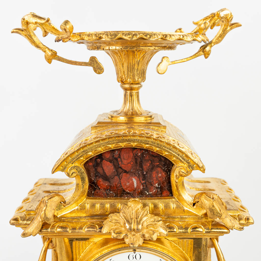 A three-piece garniture clock, inlaid with red marble and standing on wood bases. (H:38cm)