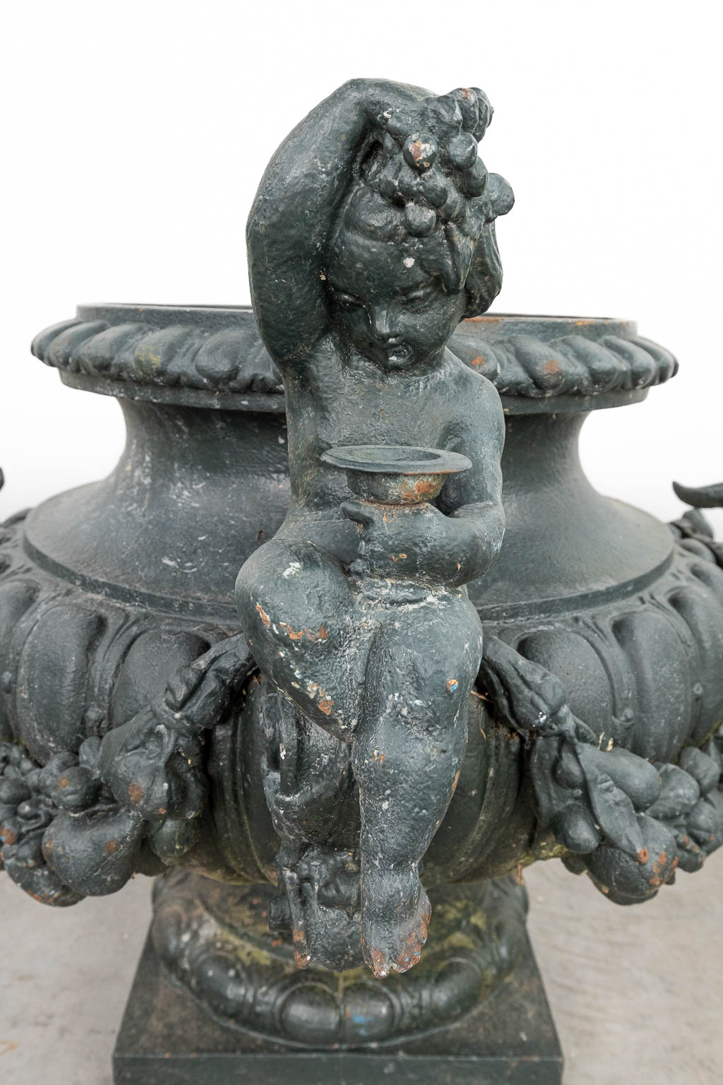 A set of 3 large garden vases made of cast iron, decorated with putti and ram