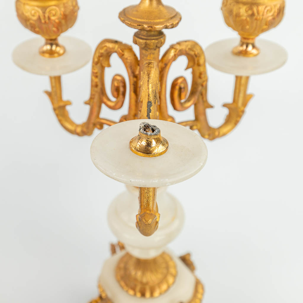 Een driedelige schouwgarnituur gemaakt uit verguld kunstbrons en albast, staande onder drie globes (H:31cm)