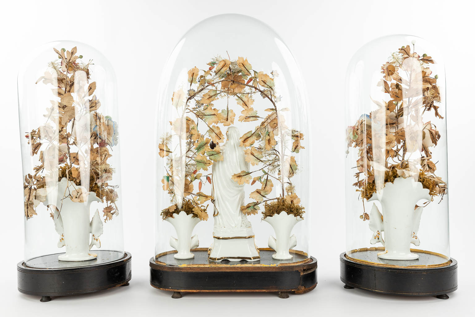 Een driedelige schouwgarnituur met een collectie Vieux Bruxelles bloemenvazen en Madonna met kind onder globes. (H:60cm)