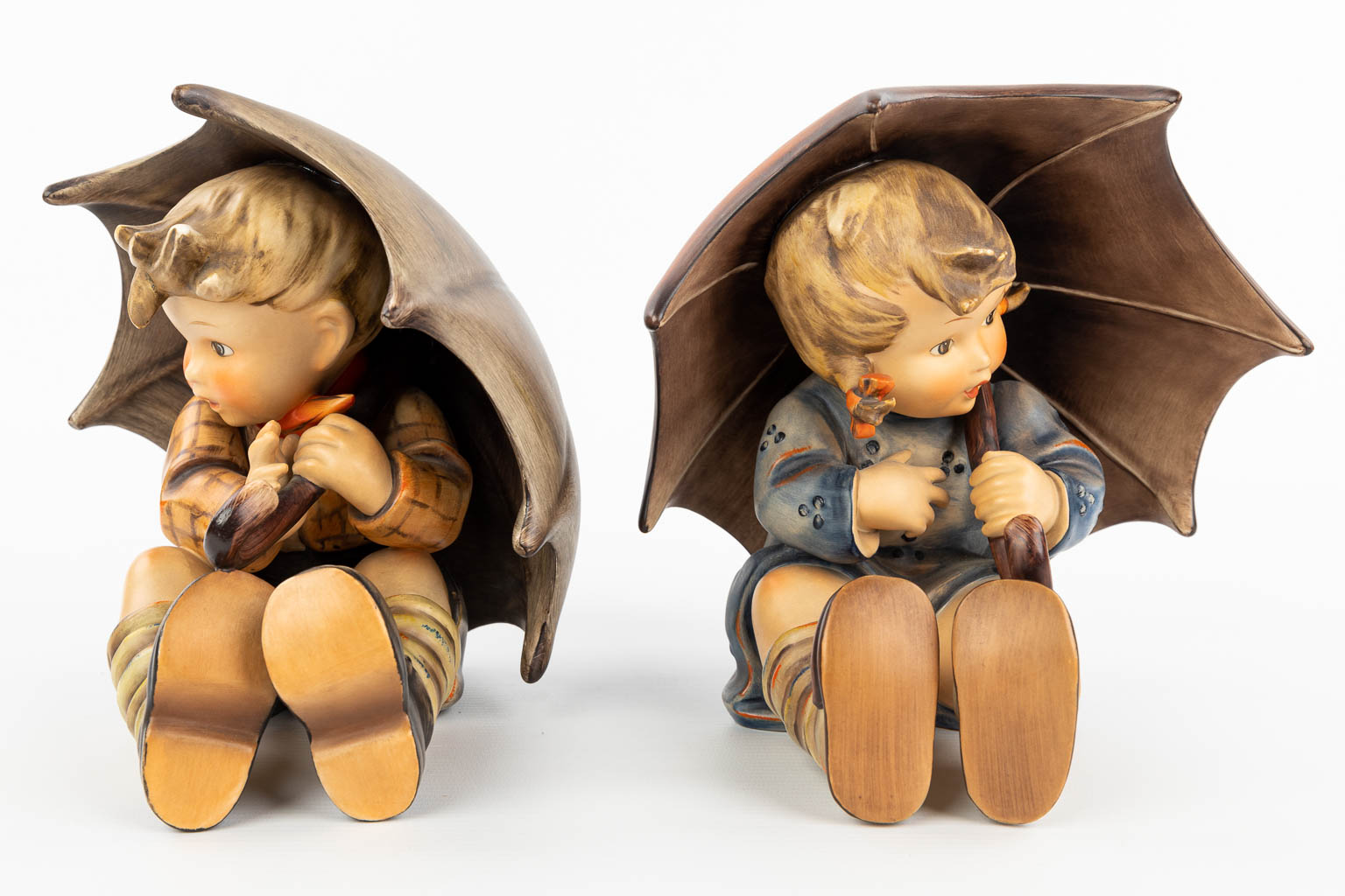A collection of 2 statues of children with an umbrella made by Hummel. (H:19cm)