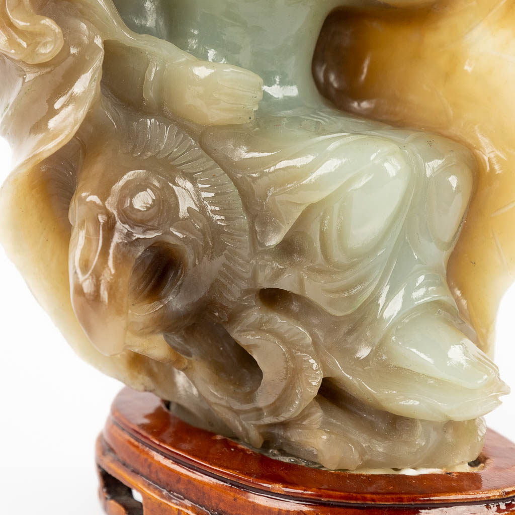 A Chinese, bicoloured Jade figurine of Guan-yin in a lotus flower. 20th C. (D:10 x W:10 x H:16 cm)