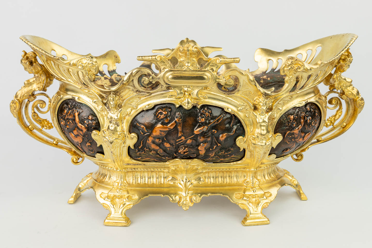 Een driedelige garnituur van jardinières gemaakt uit verguld en koper en versierd met putti. (H:22cm)