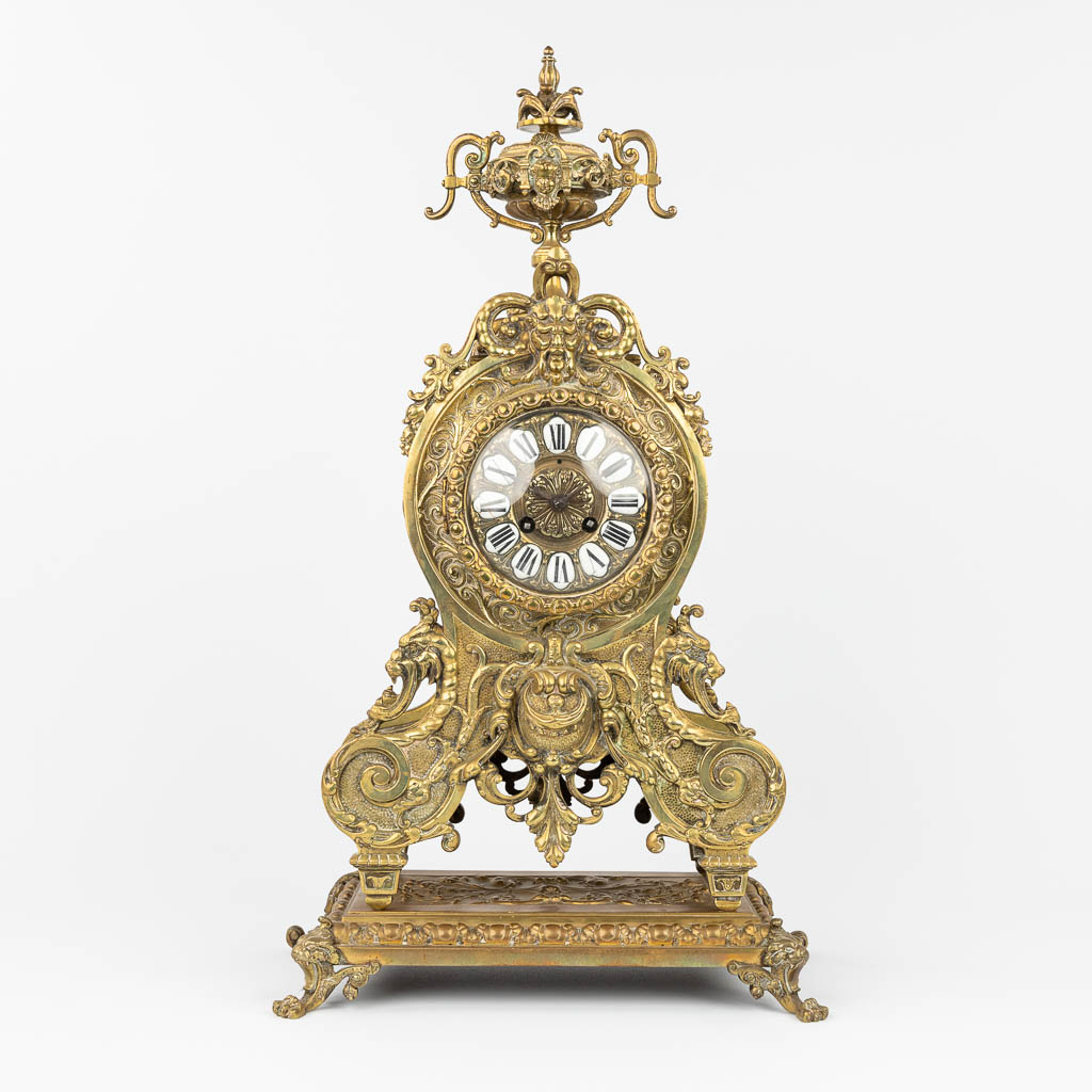 An ornate mantle clock made of bronze. (L:19 x W:32,5 x H:58 cm)