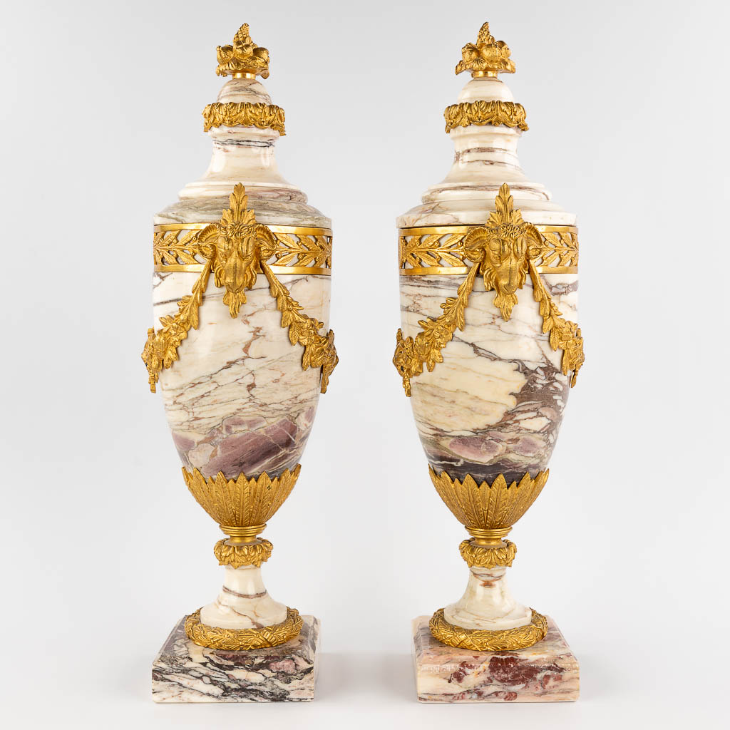Een paar cassolettes gemonteerd met verguld bronzen ramskoppen in Lodewijk XVI stijl, wit roze marmer. (W: 20 x H: 56 cm)