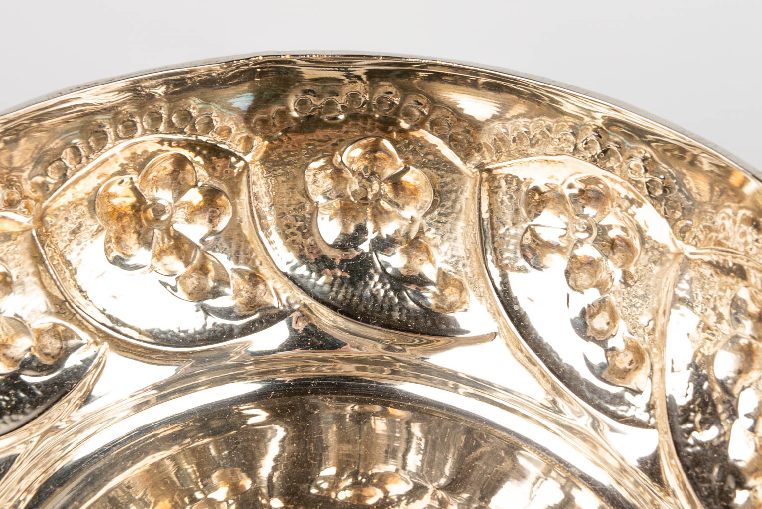 A silver-plated bowl decorated with repousse flowerdecor. 