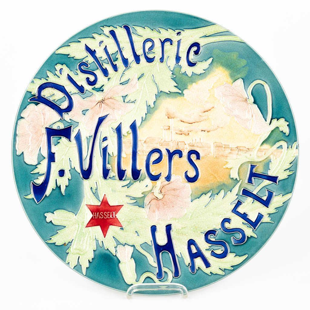 A large glazed faience plate 'Distillerie F. Villers, Hasselt'. 