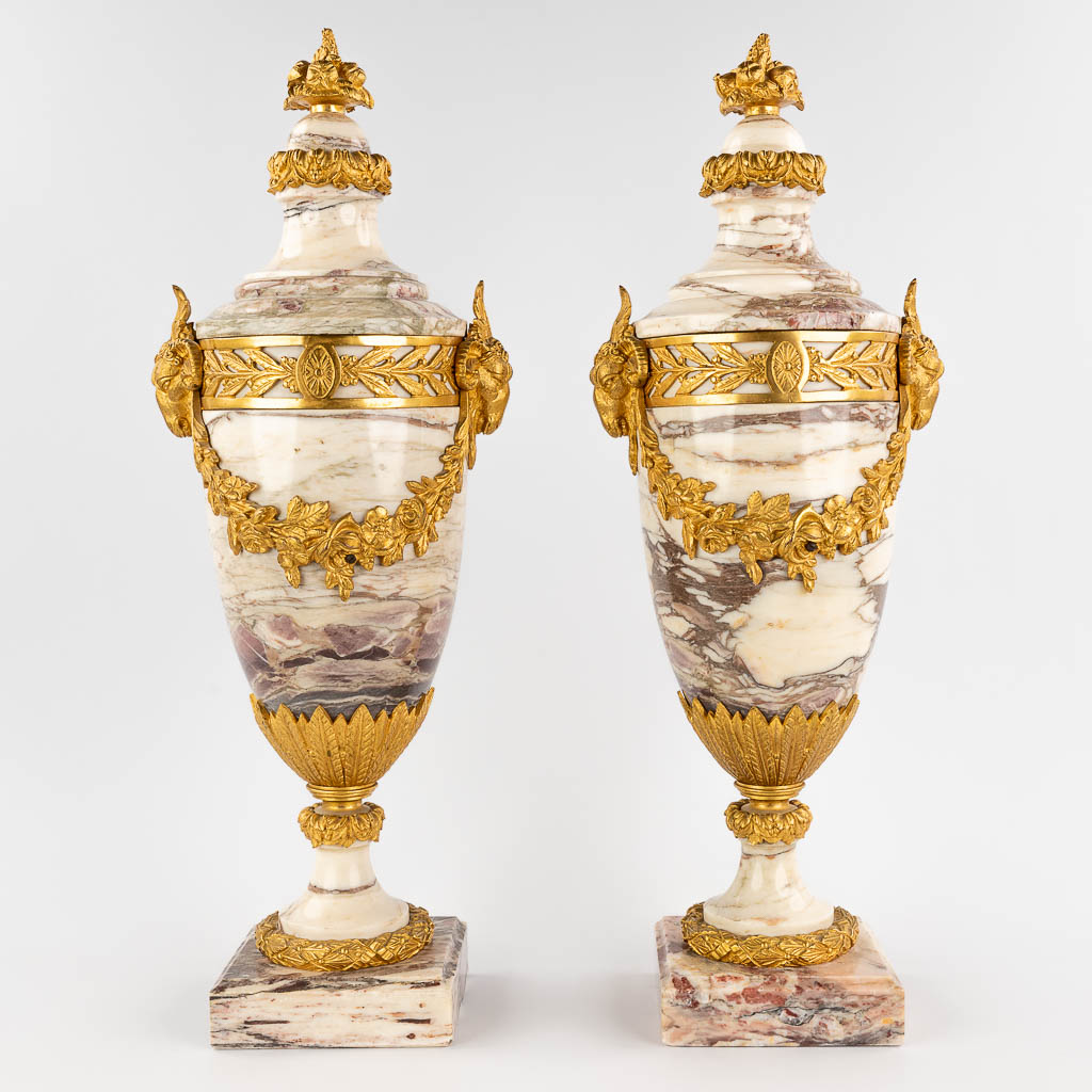Een paar cassolettes gemonteerd met verguld bronzen ramskoppen in Lodewijk XVI stijl, wit roze marmer. (W: 20 x H: 56 cm)