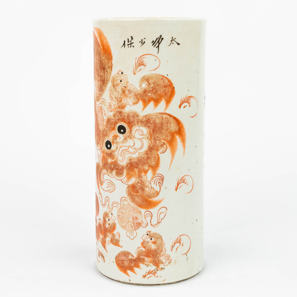 Een Chinese hoedensteun gemaakt uit porselein en versierd met rode foo hond. (H:27,5cm)