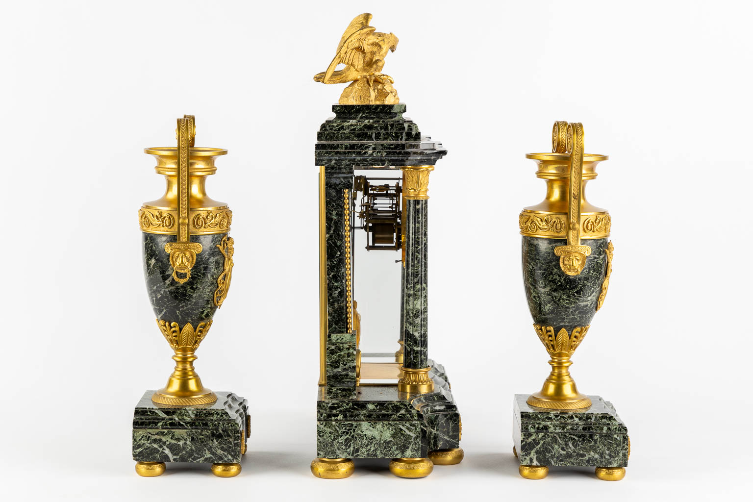 A three-piece mantle garniture clock and urns, gilt bronze on green marble, Empire style. France, 19th C. (L:16,5 x W:37 x H:51 