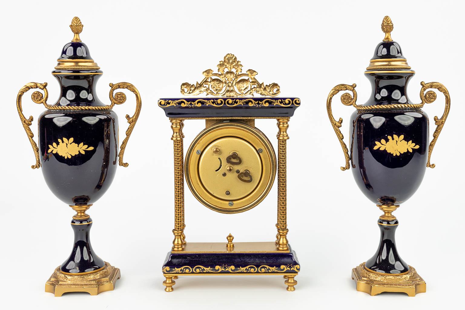 Een driedelige schouwgarnituur met klok en kandelaars gemaakt uit porselein in Sèvres stijl. (H:24cm)