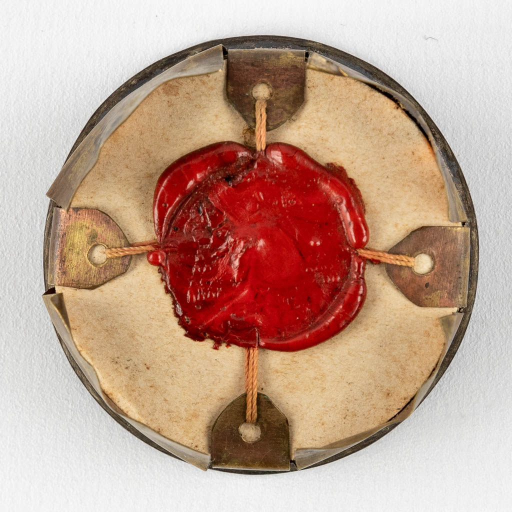 Een verzegelde Theca met relikwie: Ex Ossibus Sancti Caroli Boromaei (W:4,1 cm)