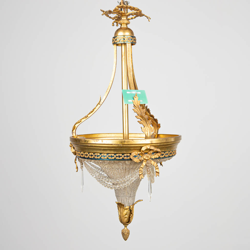 A sac-a-perles chandelier made of bronze and glass in Louis XVI style. 