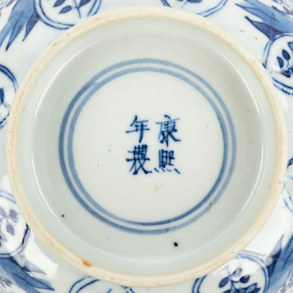 A pair of Chinese bowls made of porcelain with blue-white flower decor and marked Kangxi. (H:7,2cm)