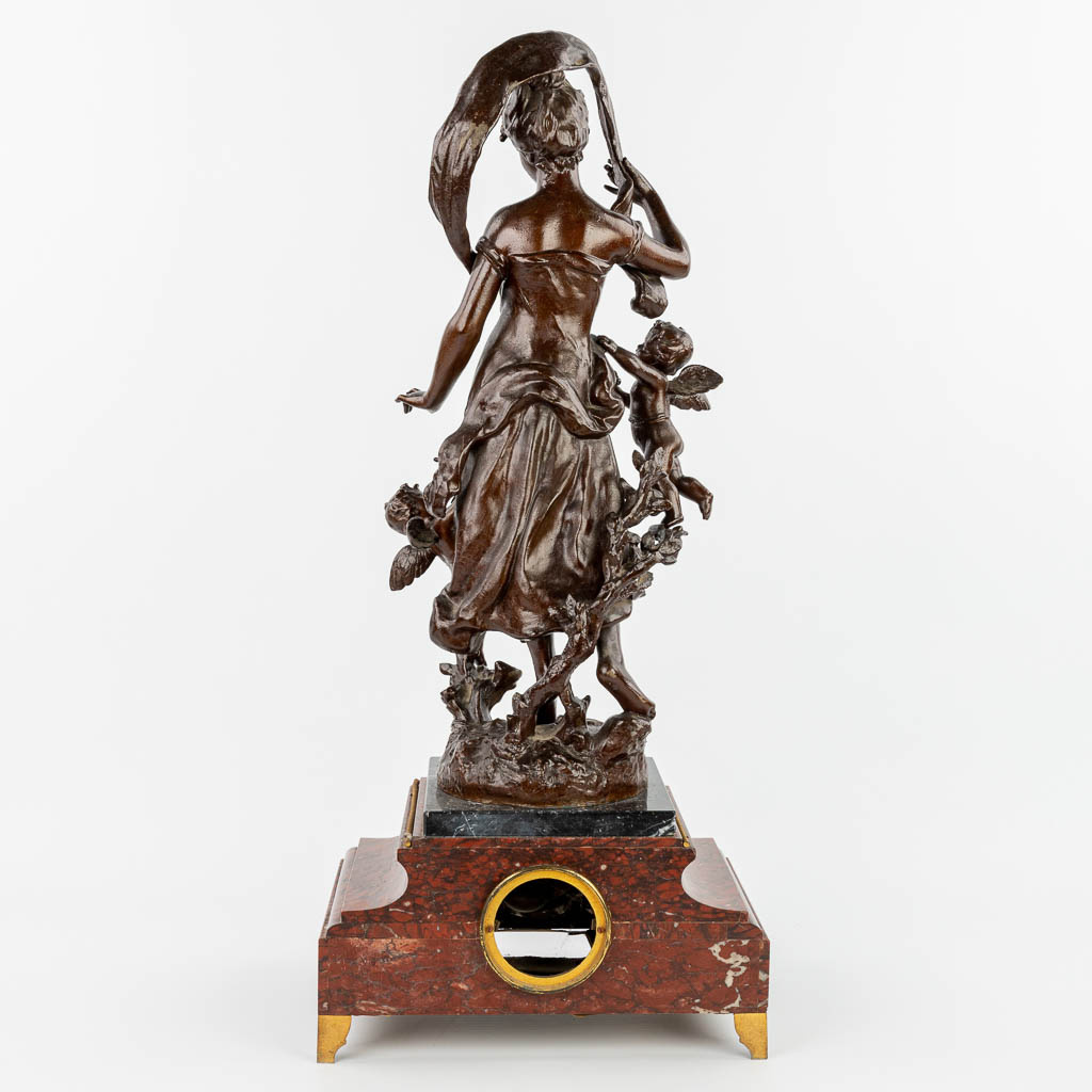 Henry KOSSOWSKI (1855-1921) A mantle clock made of red marble with a statue made of spelter and decorated with putti. (H:79cm)