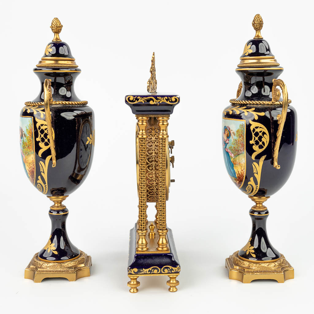 A three-piece mantle garniture with clock and side pieces made of porcelain in Sèvres style. (H:24cm)