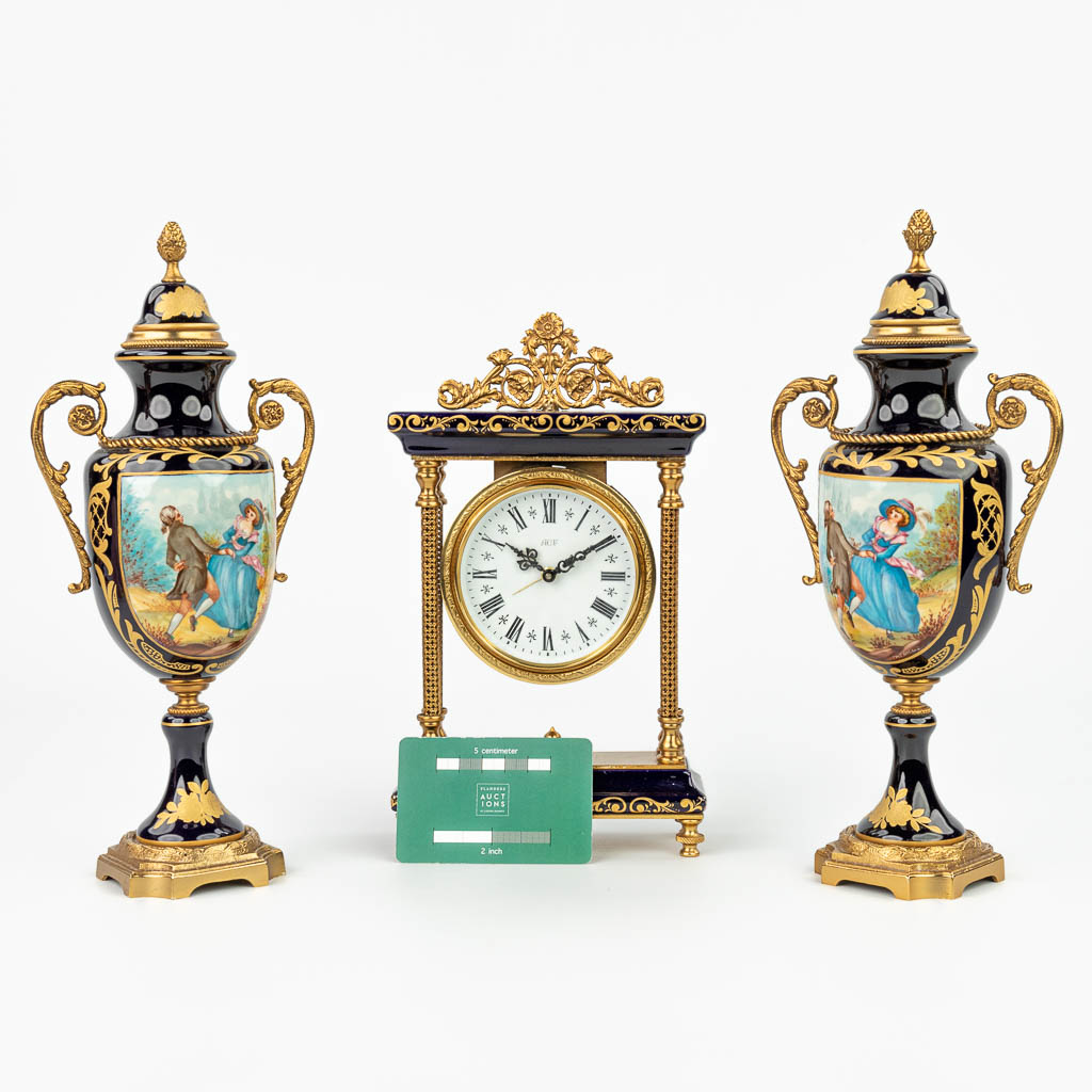 Een driedelige schouwgarnituur met klok en kandelaars gemaakt uit porselein in Sèvres stijl. (H:24cm)