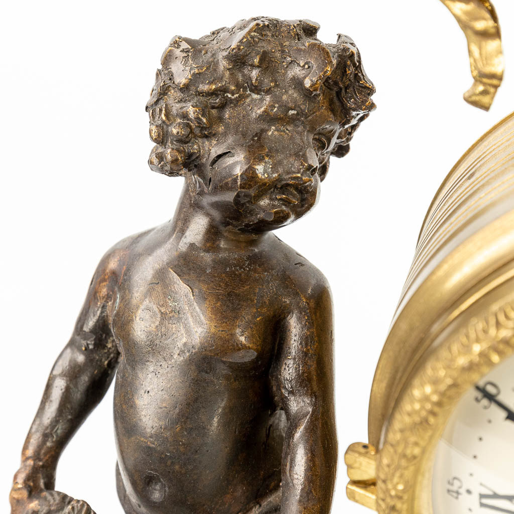 A three-piece mantle clock made of patinated and polished bronze, decorated with putti. (H:46cm)