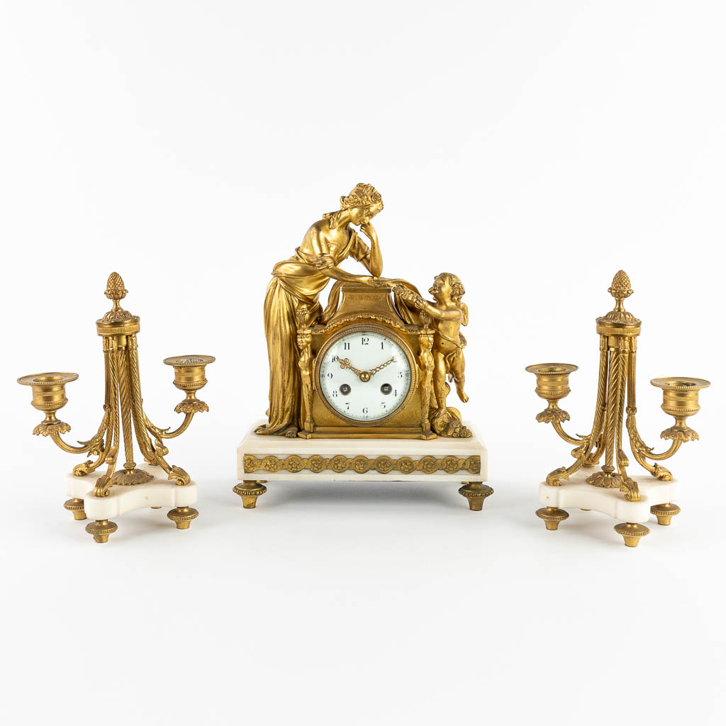 A three-piece mantle garniture clock and candelabra, gilt bronze. 19th C. (D:11,5 x W:22,5 x H:28 cm)