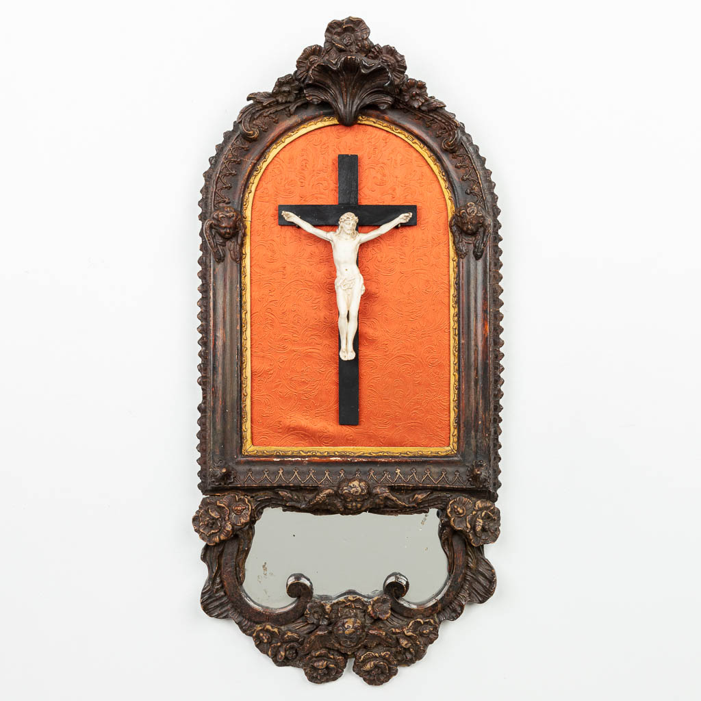 Een houtsculptuur met biscuit Corpus Christi, afgewerkt met een spiegeltje en een engel. (H:71cm)