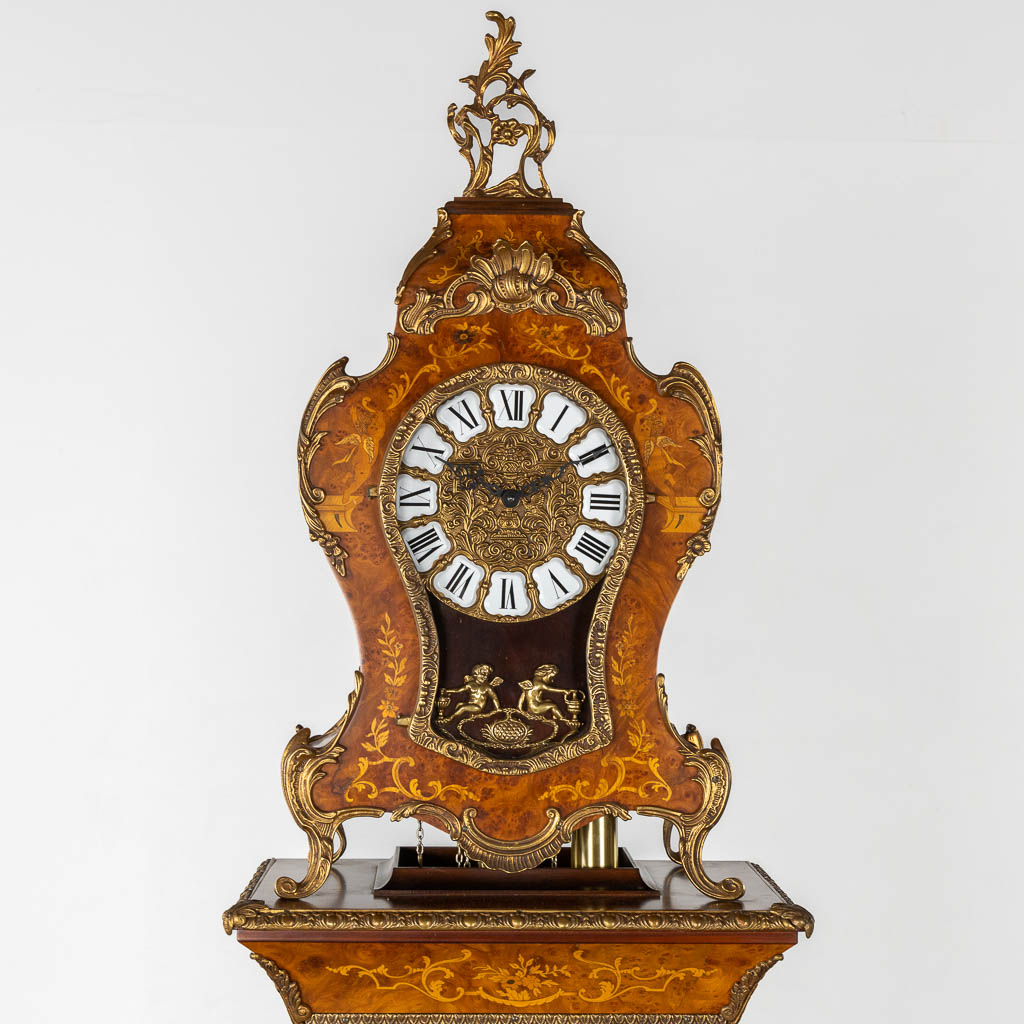 A cartel clock on a pedestal, Westminster movement, marquetry inlay and mounted with bronze. (L:29 x W:47 x H:190 cm)