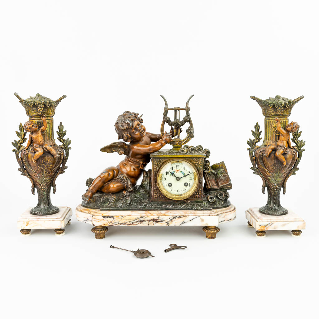 Een driedelige schouwgarnituur met klok gemaakt uit kunstbrons, versierd met putti. (H:33cm)