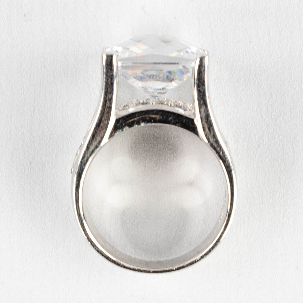 Een ring met grote vierkante gefacetteerde steen/glas, en kleinere stenen. Zilver, gemerkt 925.