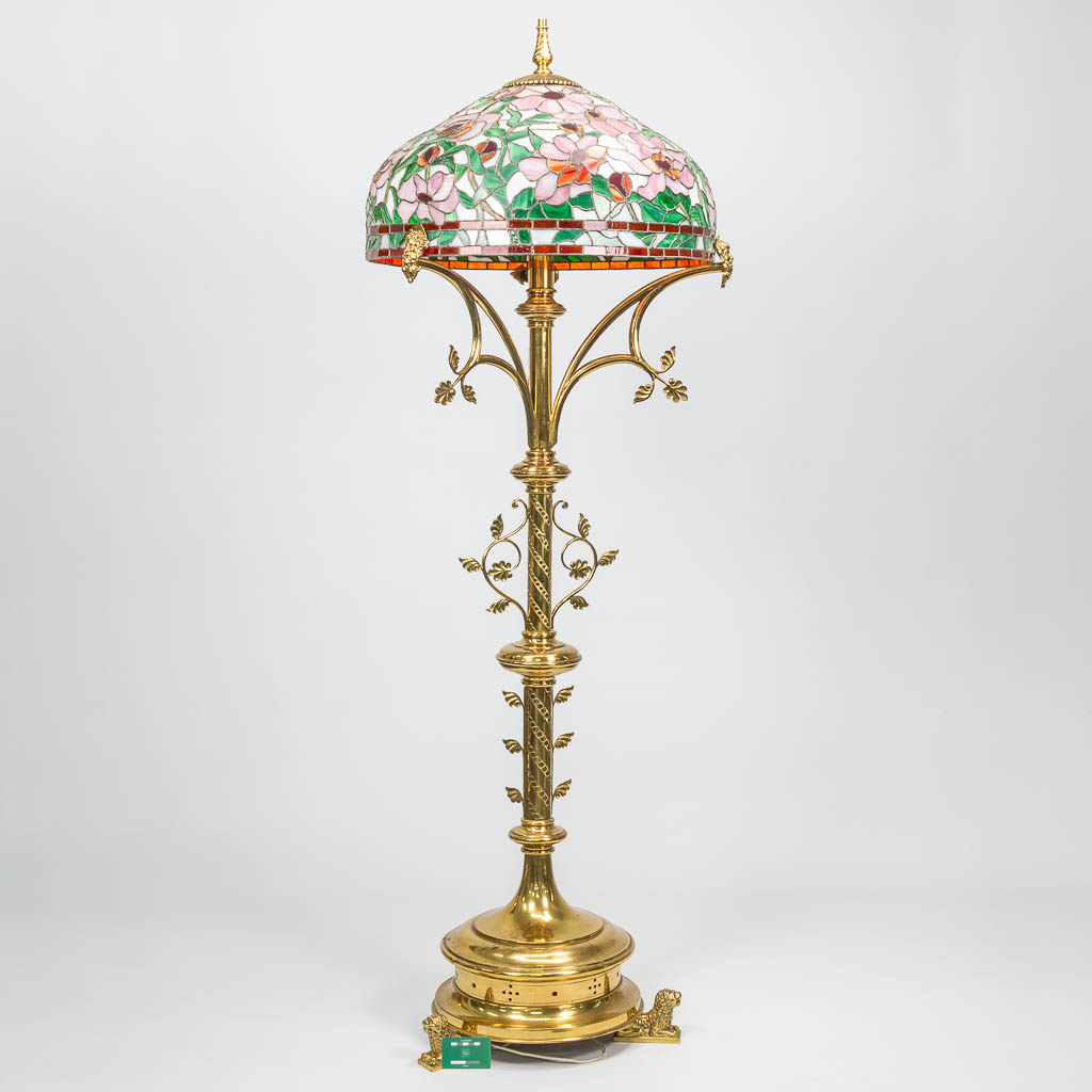 Een grote staande lamp gemaakt uit koper met een lampenkap in Tiffany Stijl. 