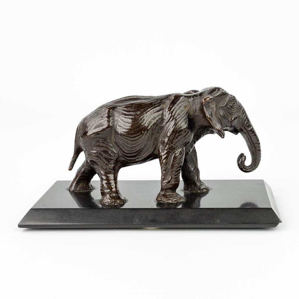 Een beeld van een olifant gemaakt uit brons en gemonteerd op een zwart marmer sokkel. (H:8cm)