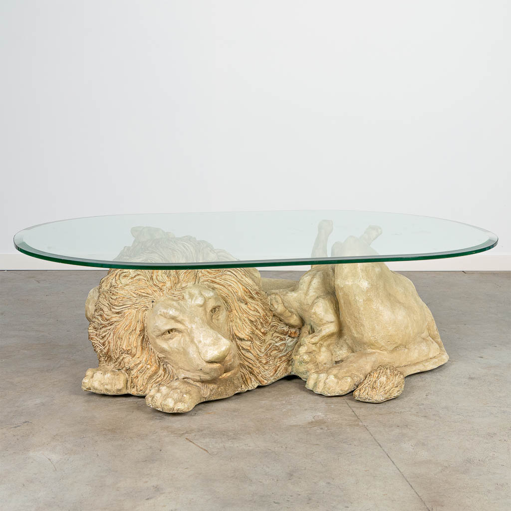 A coffee table in the shape of a lion with cubs, with a glass tabletop.