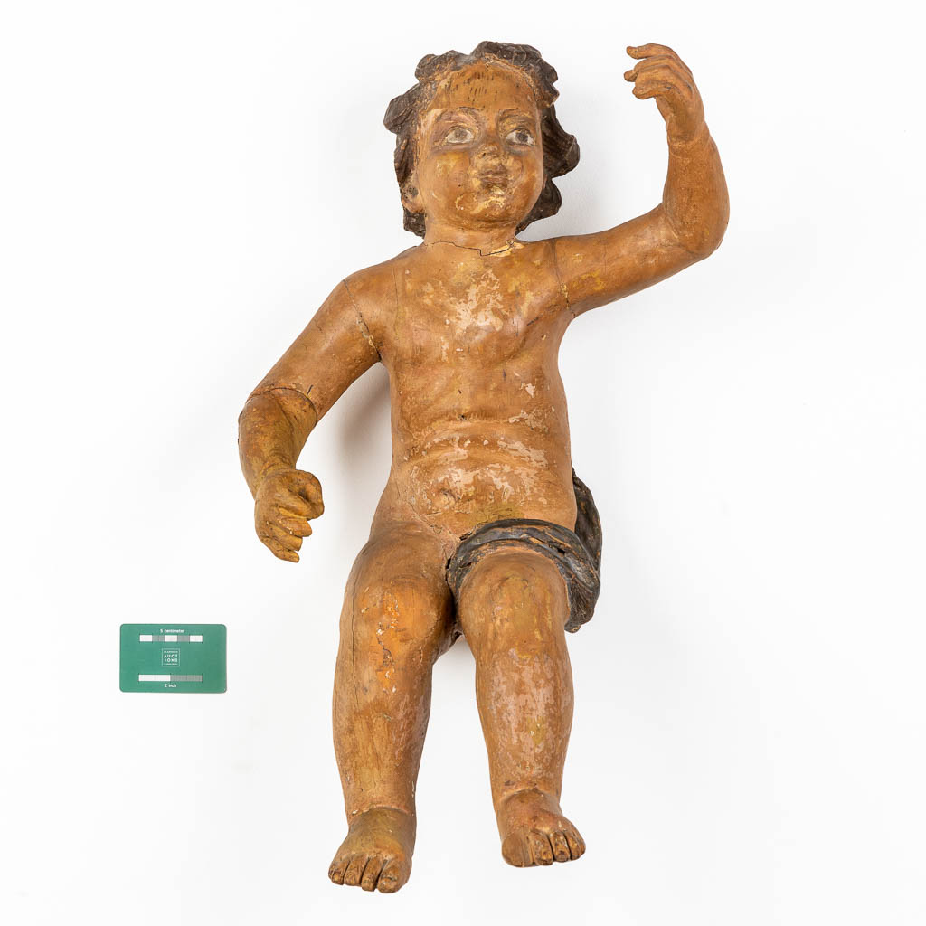 Een antieke figuur van een putto, gesculpteerd en gepatineerd hout. 18de eeuw. (L:35 x W:34 x H:67 cm)