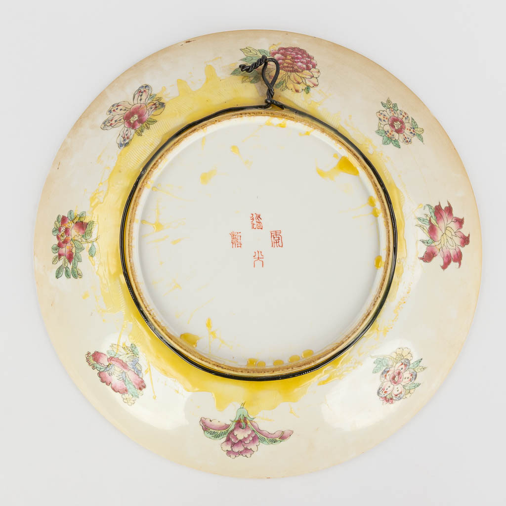 A Chinese Famille Rose plate, decorated with warriors, peaches and antiquities. 19th/20th C. (D:45,5 cm)