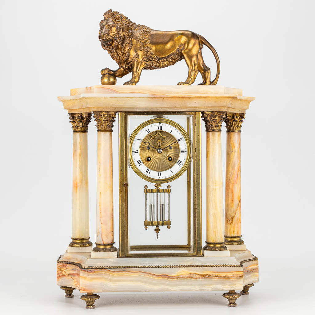 Een schouwklok gemaakt uit albast en versierd met een bronzen leeuw in neoklassieke stijl (H:52cm)