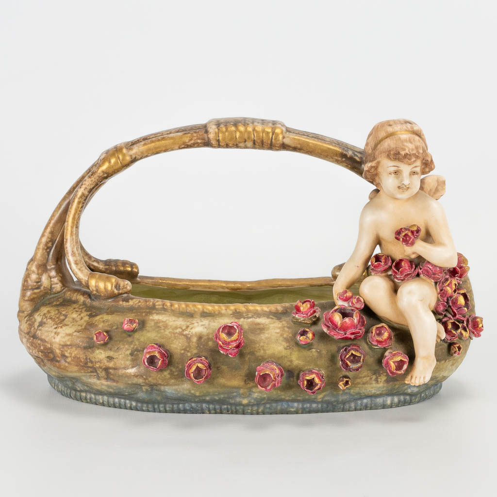 Een mand met bloemen en een engel, gemaakt uit faience in Oostenrijk en gemerkt Amphora. 